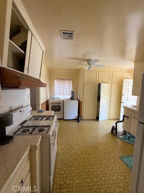 14594 Dyer St, Sylmar, CA 91342 - kitchen featuring white gas range oven, tile counters, washing machine and dryer, a ceiling fan, and white cabinetry