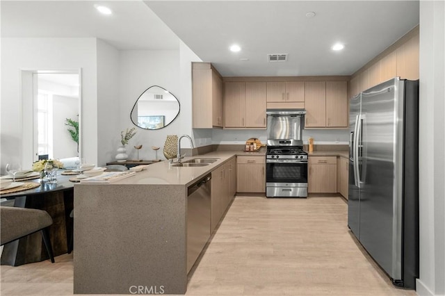 168 S Monterey St Unit 502, Alhambra, CA 91801 - kitchen with stainless steel appliances, light brown cabinetry, a peninsula, light wood-style flooring, and under cabinet range hood