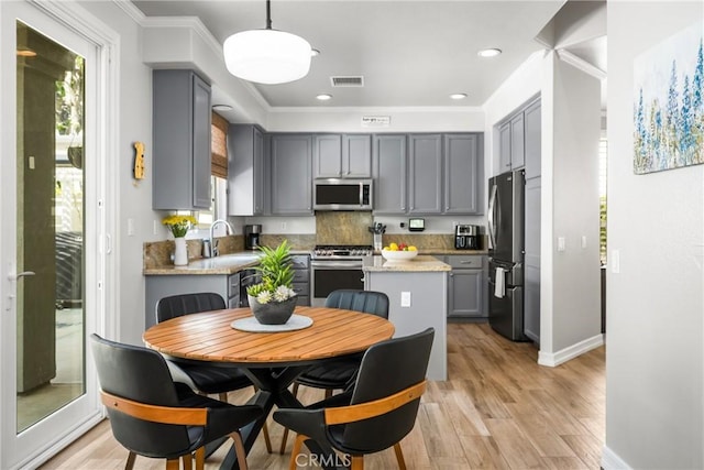 8507 E Heatherview Ln, Orange, CA 92869 - kitchen with appliances with stainless steel finishes, gray cabinetry, crown molding, tasteful backsplash, and light wood finished floors
