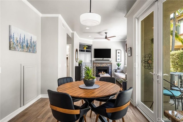 8507 E Heatherview Ln, Orange, CA 92869 - dining area featuring wood finished floors, ceiling fan, a warm lit fireplace, ornamental molding, and recessed lighting