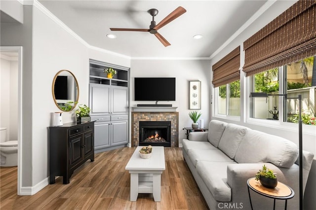 8507 E Heatherview Ln, Orange, CA 92869 - living room featuring a ceiling fan, recessed lighting, wood finished floors, a lit fireplace, and ornamental molding