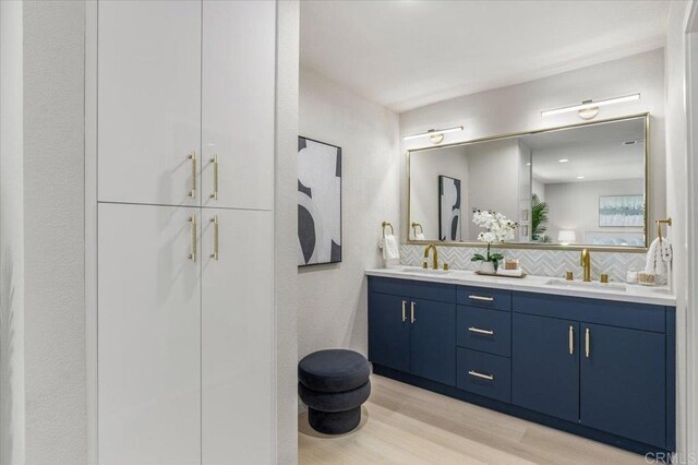 7911 Terraza Disoma, Carlsbad, CA 92009 - bathroom with double vanity, wood finished floors, and decorative backsplash