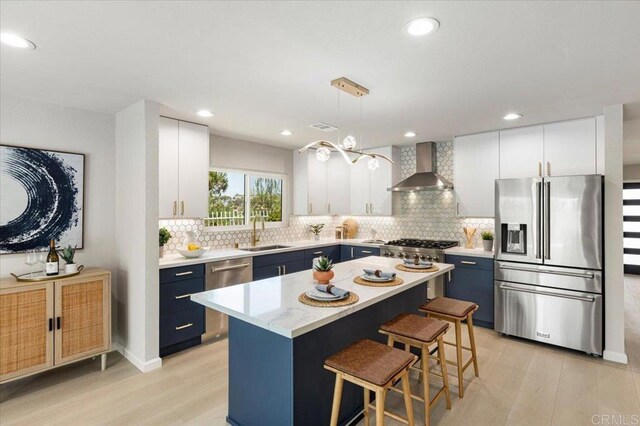 7911 Terraza Disoma, Carlsbad, CA 92009 - kitchen featuring stainless steel appliances, wall chimney range hood, blue cabinetry, a kitchen breakfast bar, and light wood-style floors