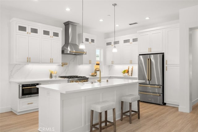 5 Gazania Ct, Chico, CA 95926 - kitchen featuring appliances with stainless steel finishes, wall chimney range hood, decorative backsplash, white cabinets, and light wood finished floors