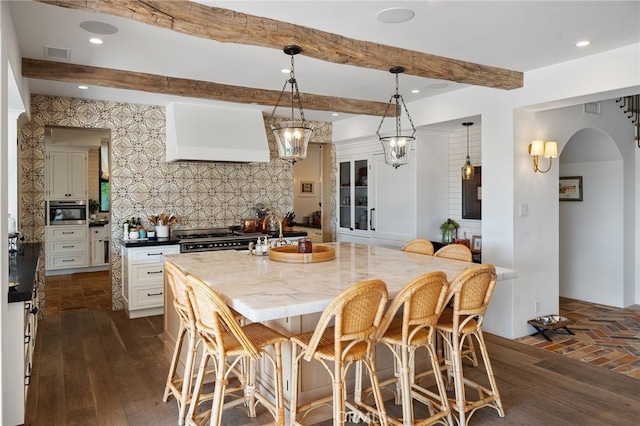 30671 Steeplechase Dr, San Juan Capistrano, CA 92675 - kitchen with beam ceiling, tasteful backsplash, wall chimney range hood, gas range, and a breakfast bar area