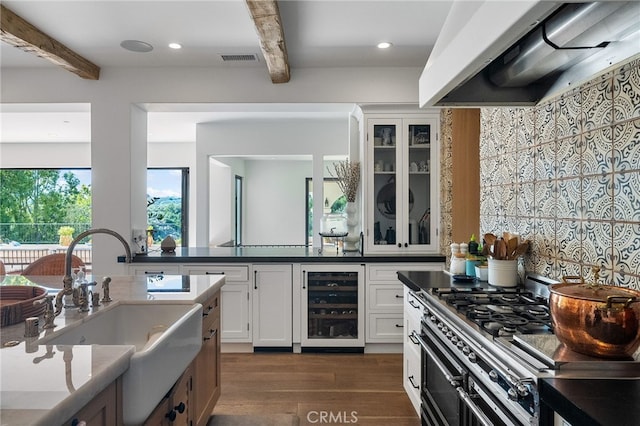 30671 Steeplechase Dr, San Juan Capistrano, CA 92675 - kitchen with wine cooler, range hood, beamed ceiling, stainless steel range with gas cooktop, and dark wood-style floors