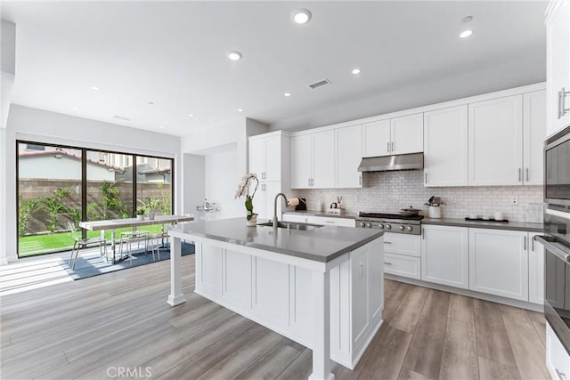 183 Plum Lily, Irvine, CA 92618 - kitchen with light wood-type flooring, tasteful backsplash, white cabinetry, dark countertops, and recessed lighting