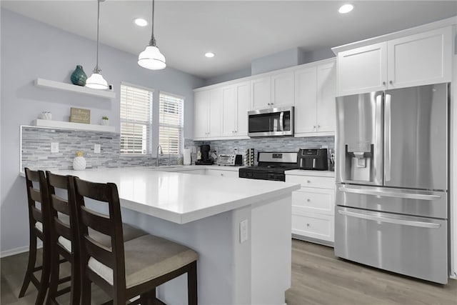 875 Iris Way Unit B, Azusa, CA 91702 - kitchen with stainless steel appliances, a kitchen bar, decorative backsplash, white cabinets, and a peninsula