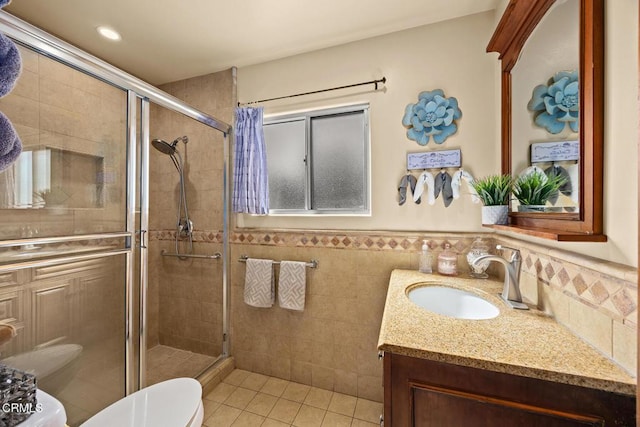 215 Bridewell St, Los Angeles, CA 90042 - full bathroom featuring vanity, tile patterned flooring, a shower stall, tile walls, and a wainscoted wall