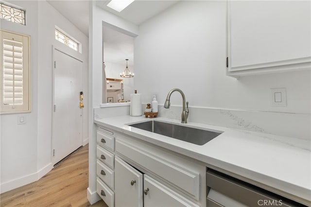 17202 Corbina Ln Unit 103, Huntington Beach, CA 92649 - kitchen featuring light wood-type flooring, light countertops, dishwashing machine, and a chandelier