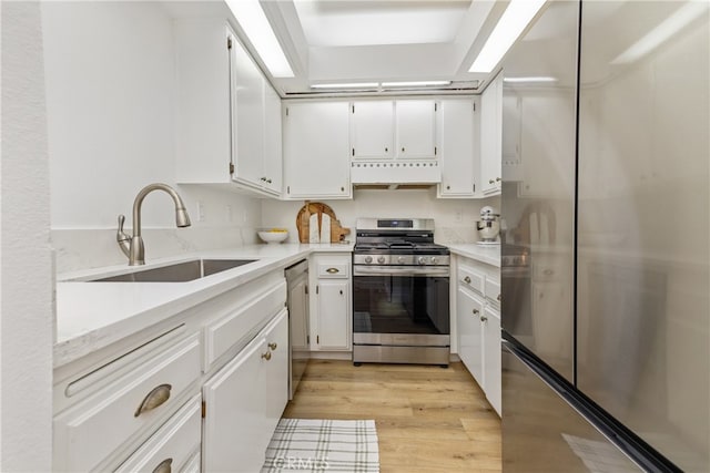 17202 Corbina Ln Unit 103, Huntington Beach, CA 92649 - kitchen featuring appliances with stainless steel finishes, exhaust hood, white cabinetry, light wood-style floors, and light countertops