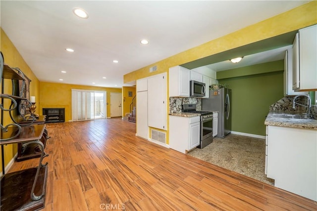 14947 Dickens St Unit 3, Sherman Oaks, CA 91403 - kitchen with appliances with stainless steel finishes, white cabinets, tasteful backsplash, open floor plan, and light wood-style floors