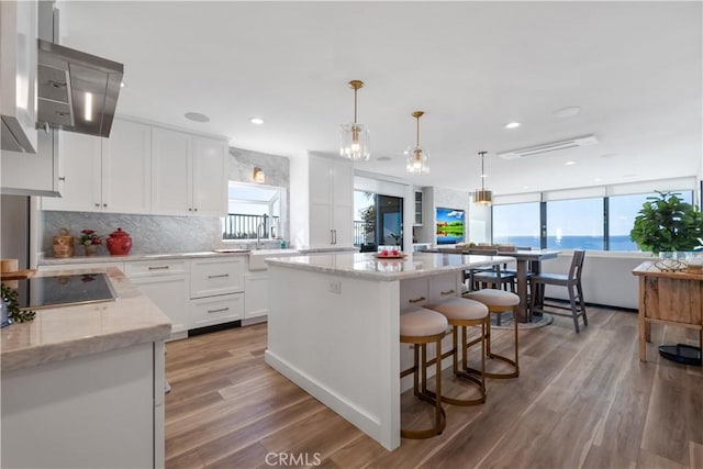 335 W I St, Encinitas, CA 92024 - kitchen featuring black electric cooktop, a center island, backsplash, white cabinetry, and light wood-type flooring