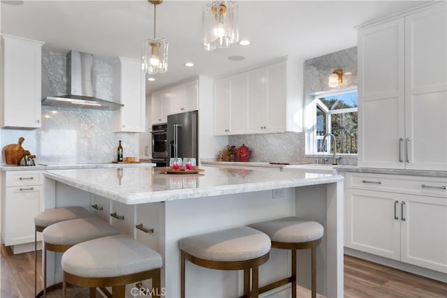 335 W I St, Encinitas, CA 92024 - kitchen featuring wall chimney exhaust hood, stainless steel appliances, a center island, white cabinets, and wood finished floors