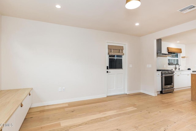 987 Bell St, Pasadena, CA 91104 - kitchen featuring stainless steel range, light wood-type flooring, wall chimney exhaust hood, white cabinets, and light countertops