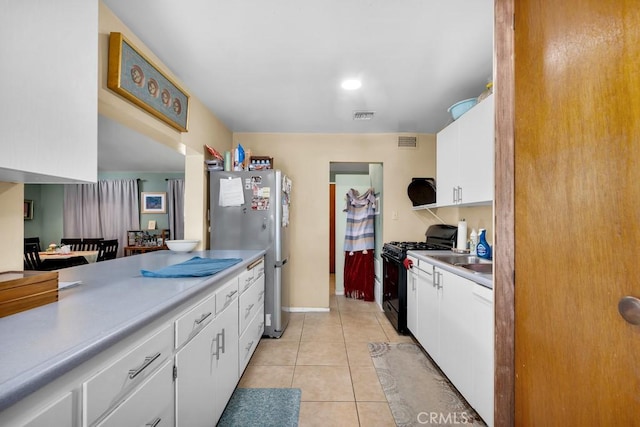 19147 Ingomar St, Reseda, CA 91335 - kitchen featuring black range with gas stovetop, freestanding refrigerator, white cabinetry, light tile patterned floors, and light countertops