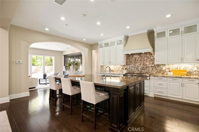 2282 E Rosecrans Ct, Brea, CA 92821 - kitchen featuring custom exhaust hood, arched walkways, a kitchen bar, dark wood-type flooring, and a kitchen island with sink