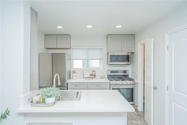 15300 Ocaso Ave Unit E102, La Mirada, CA 90638 - kitchen featuring stainless steel appliances, gray cabinets, light countertops, a peninsula, and recessed lighting