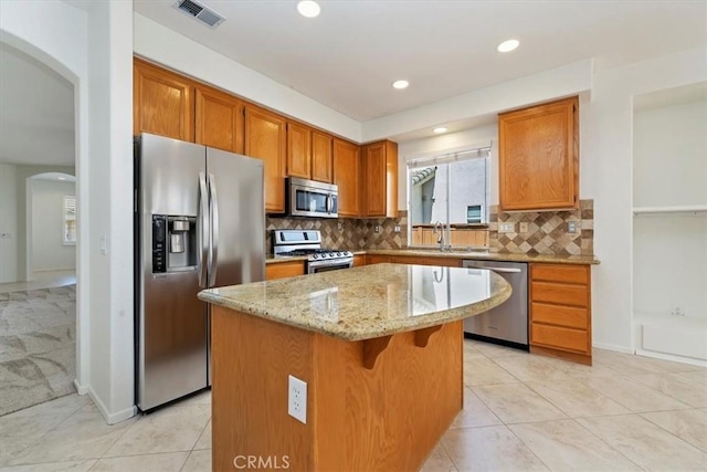 31042 Bunker Dr, Temecula, CA 92591 - kitchen with appliances with stainless steel finishes, arched walkways, a center island, light stone countertops, and tasteful backsplash