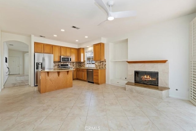 31042 Bunker Dr, Temecula, CA 92591 - kitchen featuring stainless steel appliances, open floor plan, ceiling fan, backsplash, and a center island