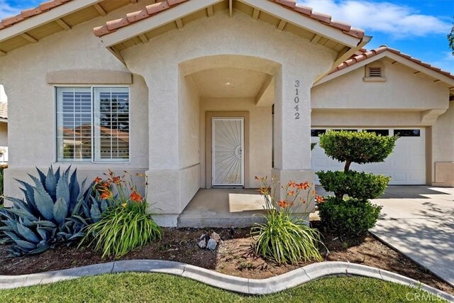 31042 Bunker Dr, Temecula, CA 92591 - property entrance with stucco siding, a garage, a tile roof, and concrete driveway