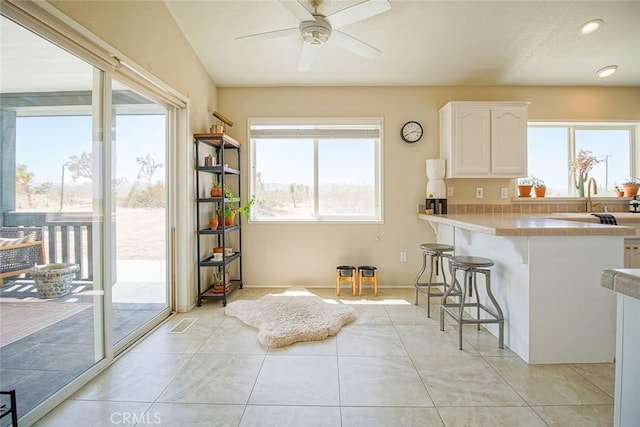 1001 Gibralter Rd, Landers, CA 92285 - kitchen featuring white cabinetry, a kitchen breakfast bar, light countertops, light tile patterned floors, and ceiling fan