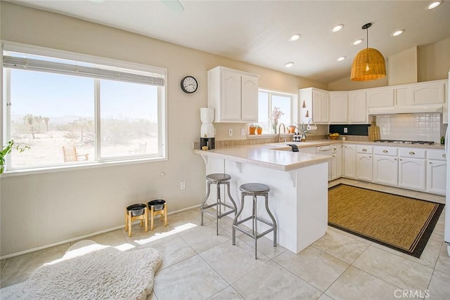 1001 Gibralter Rd, Landers, CA 92285 - kitchen with a breakfast bar area, a peninsula, white cabinetry, decorative backsplash, and light countertops
