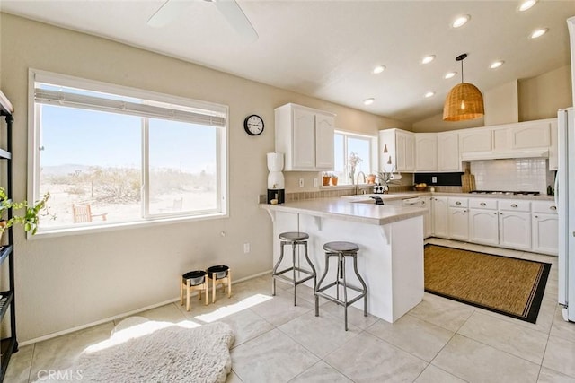 1001 Gibralter Rd, Landers, CA 92285 - kitchen with a peninsula, white cabinetry, a kitchen bar, ceiling fan, and light countertops