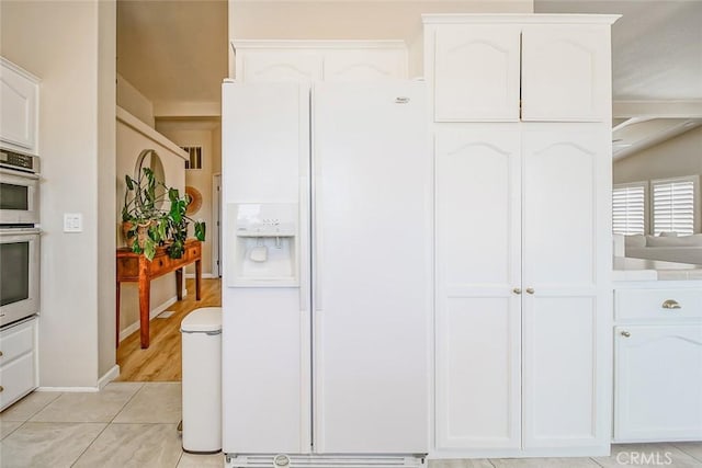 1001 Gibralter Rd, Landers, CA 92285 - kitchen featuring white refrigerator with ice dispenser, white cabinetry, double oven, and light tile patterned floors