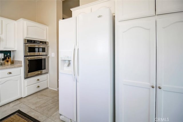 1001 Gibralter Rd, Landers, CA 92285 - kitchen with white refrigerator with ice dispenser, stainless steel double oven, white cabinets, and tile counters