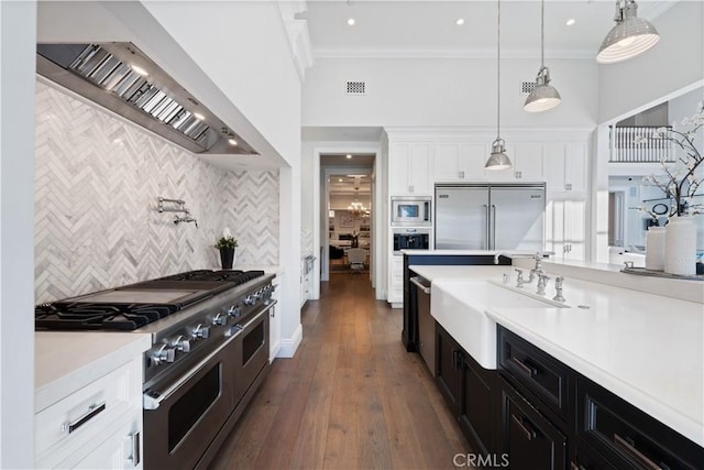 17528 Jayden Ln, Encino, CA 91316 - kitchen with built in appliances, wall chimney range hood, dark cabinetry, white cabinets, and tasteful backsplash