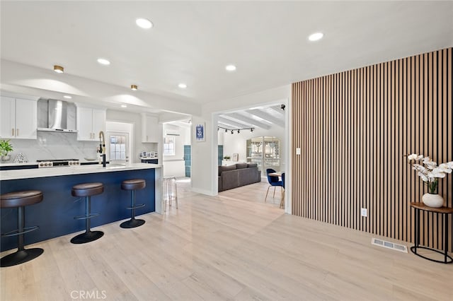 647 Magnolia Ave, Brea, CA 92821 - kitchen with wall chimney range hood, a kitchen breakfast bar, light countertops, light wood-type flooring, and recessed lighting