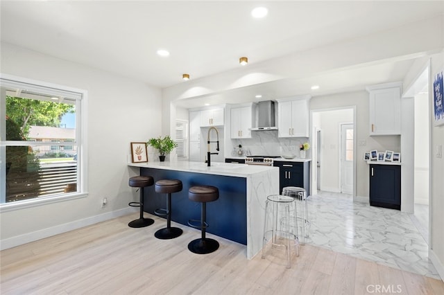 647 Magnolia Ave, Brea, CA 92821 - kitchen with wall chimney range hood, a kitchen breakfast bar, light countertops, a peninsula, and white cabinetry