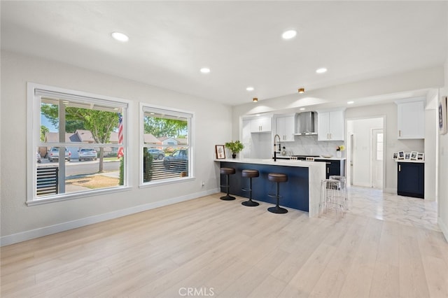 647 Magnolia Ave, Brea, CA 92821 - kitchen featuring a kitchen bar, wall chimney exhaust hood, light countertops, white cabinetry, and light wood-type flooring
