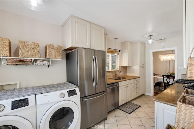 20108 Wayne Ave, Torrance, CA 90503 - kitchen featuring appliances with stainless steel finishes, washing machine and dryer, light tile patterned flooring, backsplash, and a chandelier