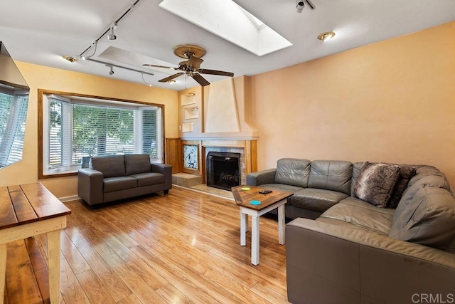 10048 Waynecrest Ln, Santee, CA 92071 - living area with rail lighting, a skylight, light wood finished floors, a tile fireplace, and ceiling fan