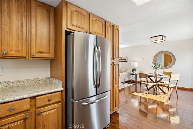 2133 Via Puerta Unit A, Laguna Woods, CA 92637 - kitchen featuring freestanding refrigerator, brown cabinetry, and dark wood finished floors