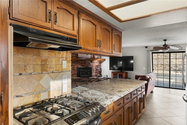 320 Casa Real Pl, Nipomo, CA 93444 - kitchen with under cabinet range hood, stainless steel range with gas cooktop, a ceiling fan, open floor plan, and brown cabinets