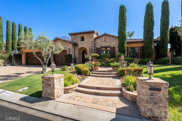 25492 Spotted Pony Ln, Laguna Hills, CA 92653 - mediterranean / spanish home featuring an attached garage, driveway, a front lawn, a tiled roof, and stone siding