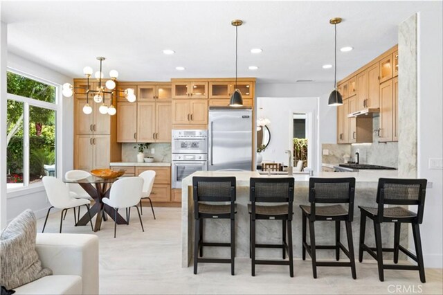 15 Glastonbury Pl, Laguna Niguel, CA 92677 - kitchen with stainless steel appliances, a peninsula, glass insert cabinets, backsplash, and a kitchen bar