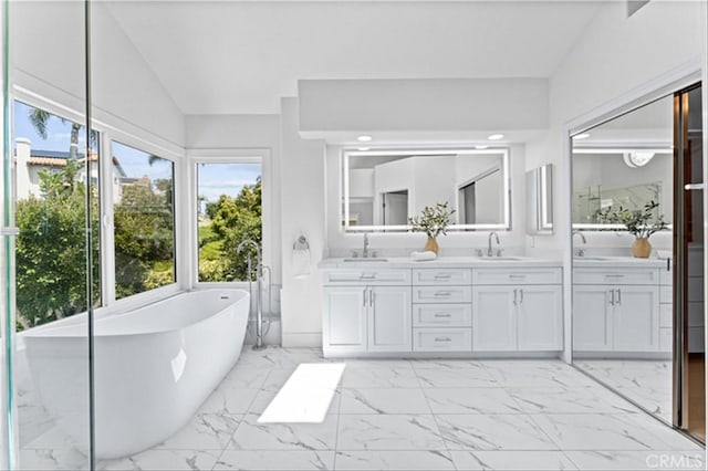 15 Glastonbury Pl, Laguna Niguel, CA 92677 - bathroom featuring healthy amount of natural light, double vanity, a soaking tub, marble finish floors, and vaulted ceiling