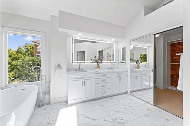15 Glastonbury Pl, Laguna Niguel, CA 92677 - bathroom featuring marble finish floors, double vanity, a freestanding bath, vaulted ceiling, and recessed lighting