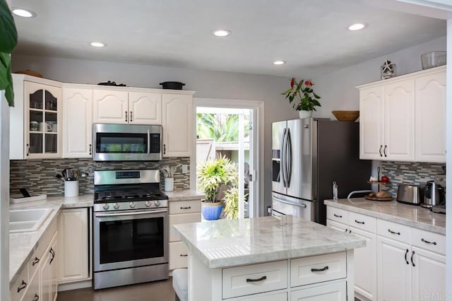 121 Cadmus St, Encinitas, CA 92024 - kitchen with appliances with stainless steel finishes, backsplash, white cabinets, glass insert cabinets, and light stone countertops