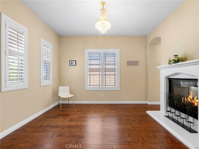 7219 Evening Star Rose Ct, Oak Hills, CA 92344 - unfurnished living room with wood finished floors, a chandelier, and a warm lit fireplace