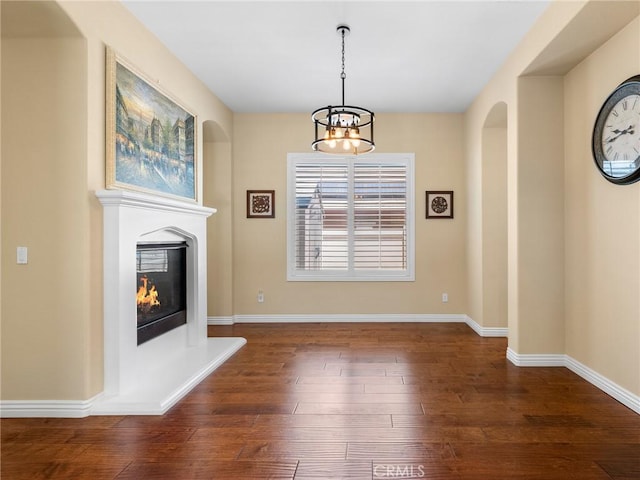 7219 Evening Star Rose Ct, Oak Hills, CA 92344 - unfurnished dining area featuring dark wood finished floors, a chandelier, a glass covered fireplace, and arched walkways