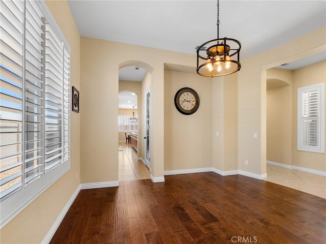 7219 Evening Star Rose Ct, Oak Hills, CA 92344 - unfurnished dining area with arched walkways, a chandelier, and wood finished floors