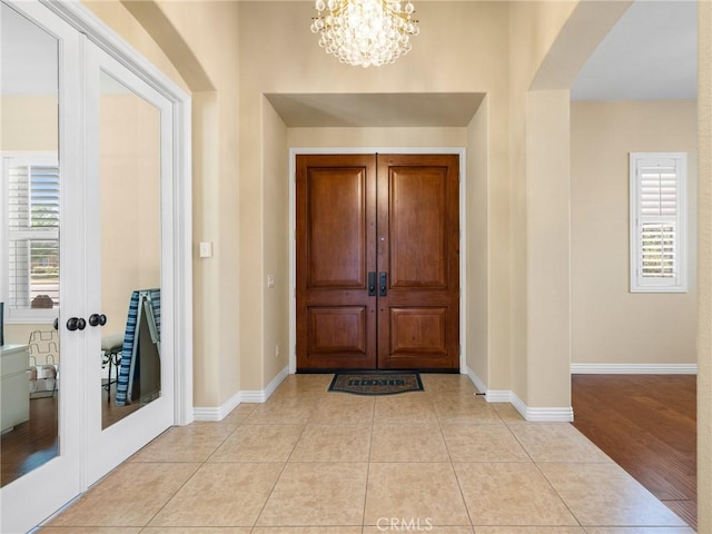 7219 Evening Star Rose Ct, Oak Hills, CA 92344 - foyer entrance featuring french doors, a chandelier, light tile patterned flooring, and arched walkways