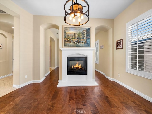 7219 Evening Star Rose Ct, Oak Hills, CA 92344 - unfurnished living room featuring wood finished floors, a glass covered fireplace, and arched walkways