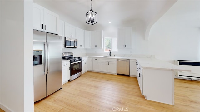1113 Pacific Ave, Long Beach, CA 90813 - kitchen featuring stainless steel appliances, a peninsula, light wood-style floors, light stone counters, and hanging light fixtures