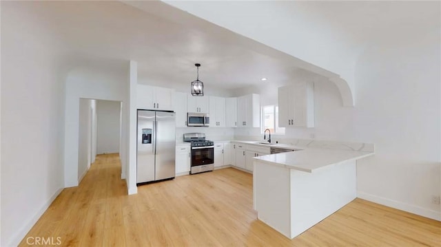 1113 Pacific Ave, Long Beach, CA 90813 - kitchen with stainless steel appliances, a peninsula, light wood-type flooring, white cabinetry, and decorative light fixtures